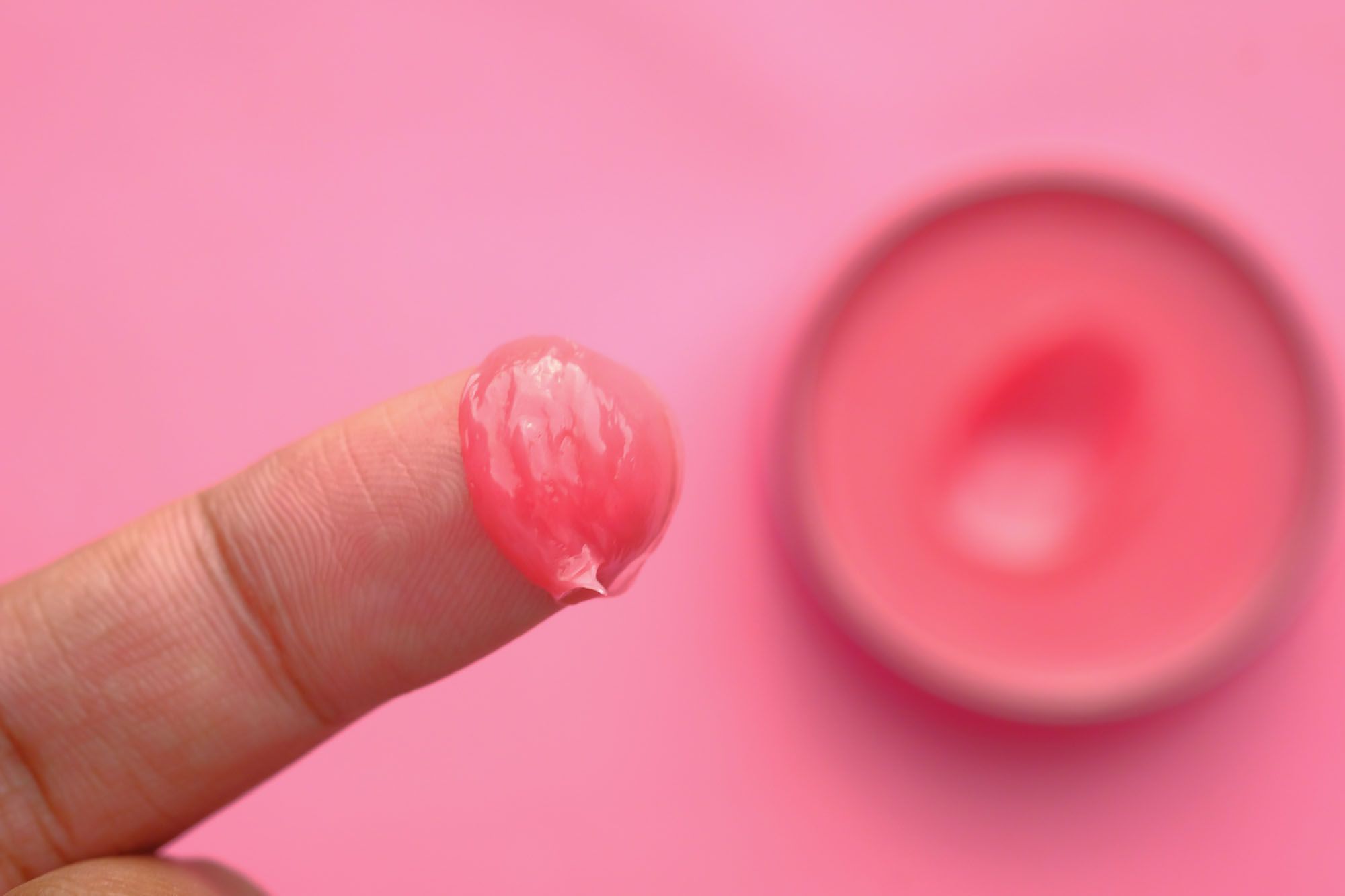Finger mit pinkem Gleitgel auf vor pinkem Hintergrund