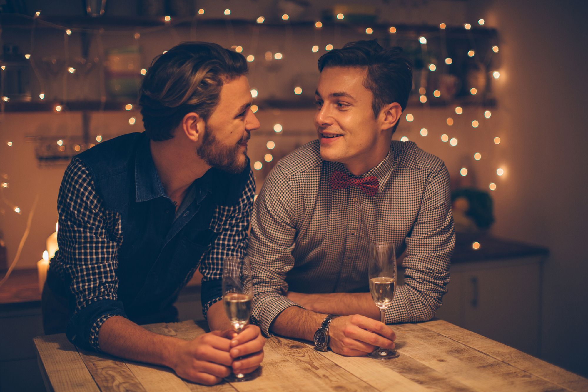 Schwules Paar, das in romantischer Atmosphäre ein Glas Sekt trinkt