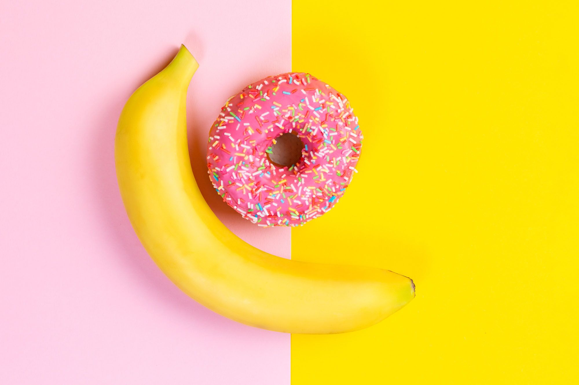 Banane und Donut auf gelb-rosa Hintergrund