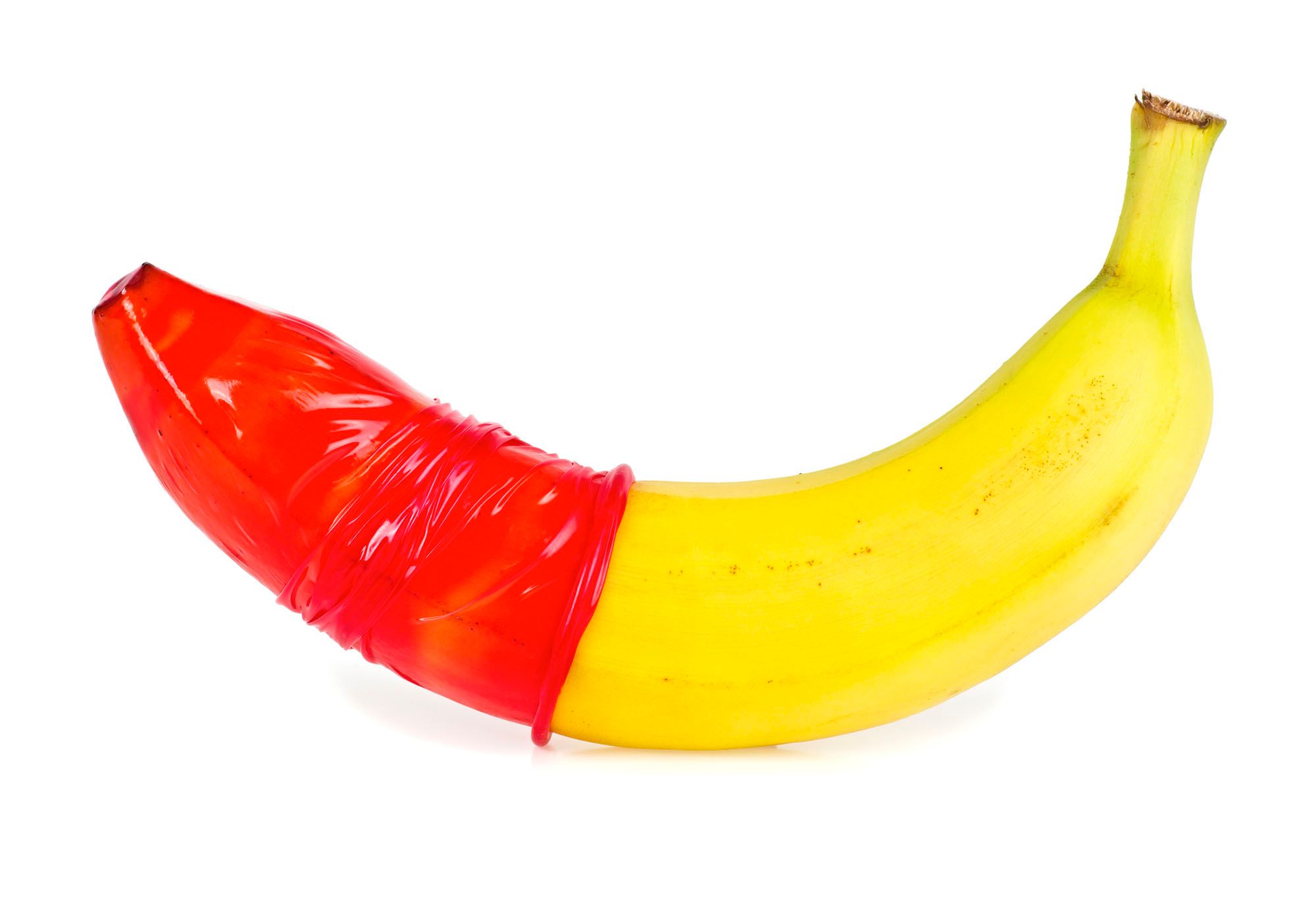 Banane, über die ein rotes Kondom gezogen ist
