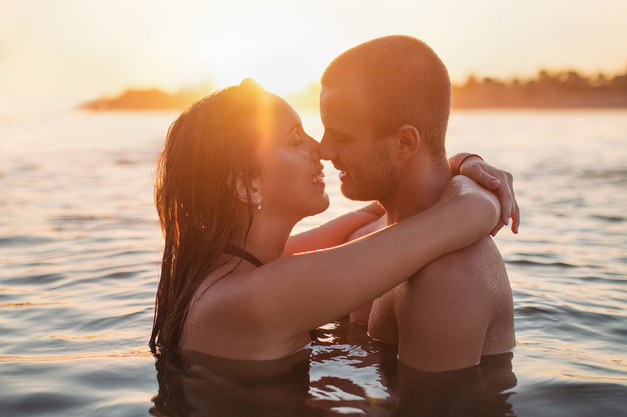 Paar im See küsst sich, Sonne geht unter
