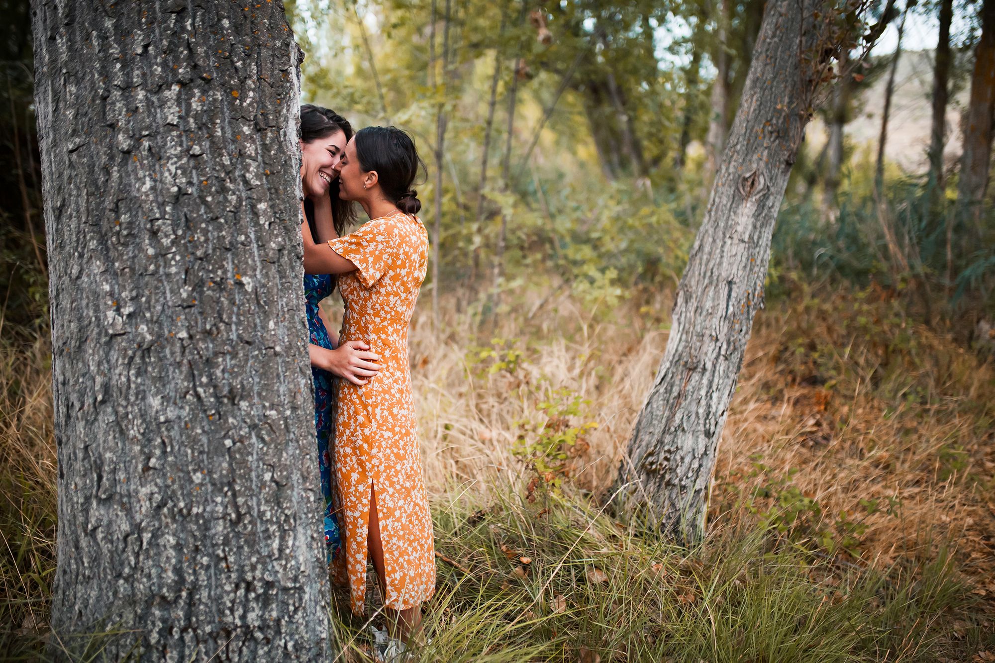 2 Frauen, die sich hinter einem Baum küssen