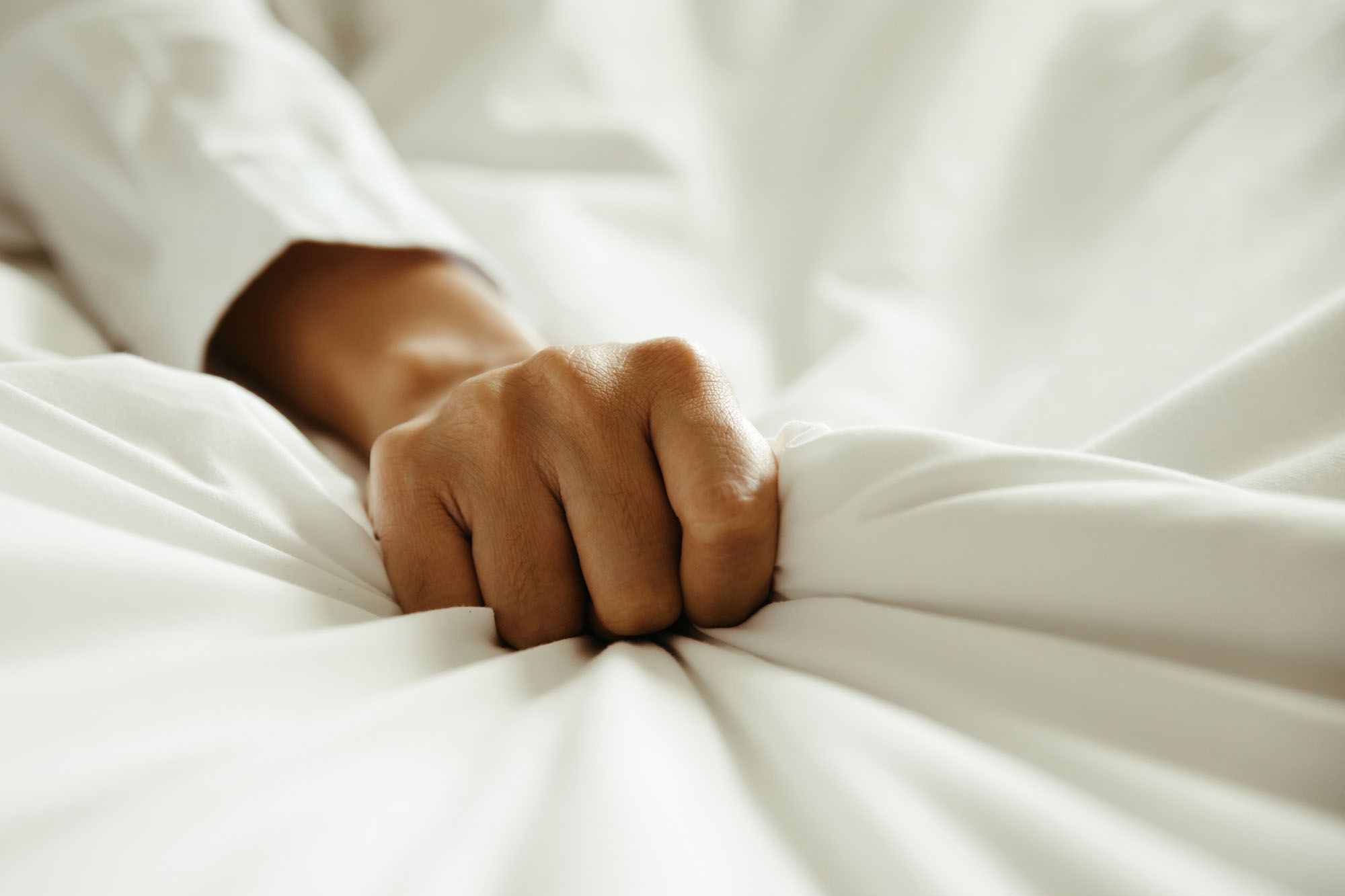 Hand, die sich in eine Bettdecke krallt