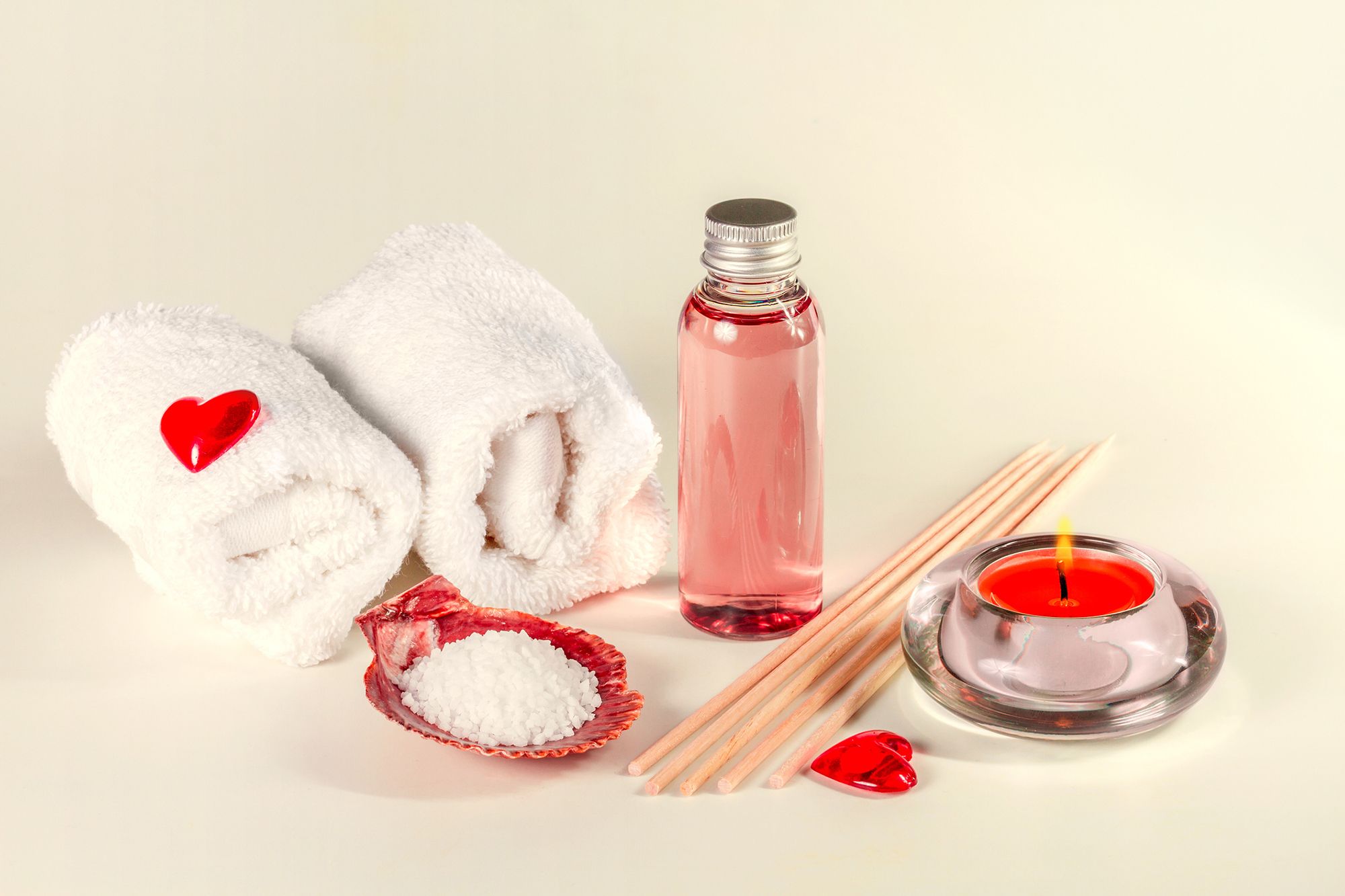 Handtücher, Holzstäbchen, Massageöl und Massagekerze auf beigem Hintergrund