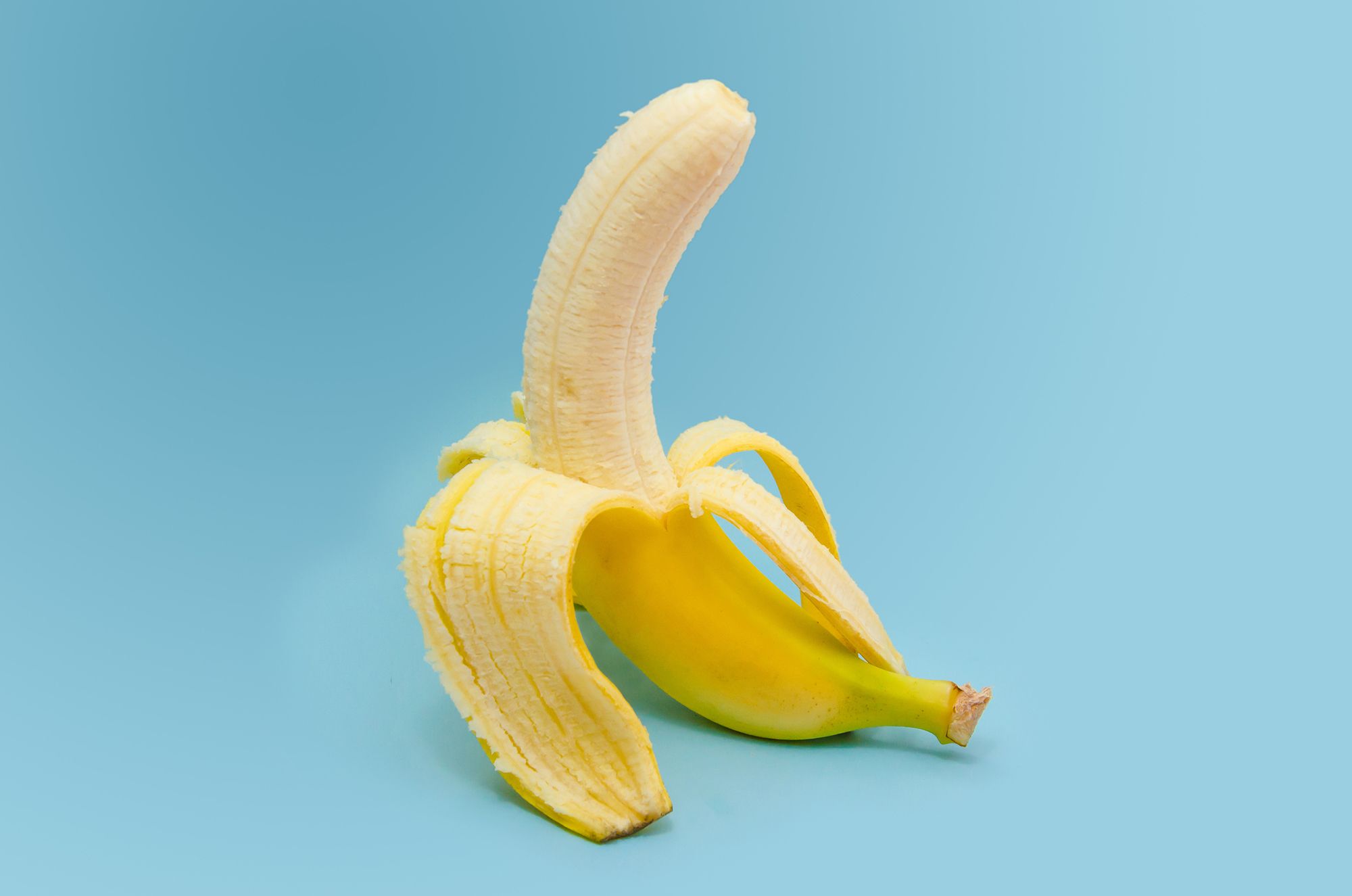Halb geschälte Banane auf hellblauem Hintergrund