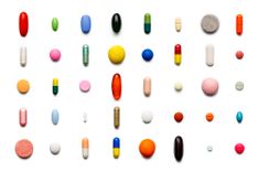 Viele bunte Pillen die geordnet auf einem weißen Hintergrund liegen