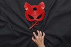 Rote Tiermaske aus Leder auf schwarzem Stoff-Hintergund
