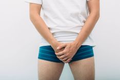 Mann in Unterhose verschränkt die Hände vor seinem Schritt
