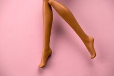 Beine einer Puppe vor pinkem Hintergrund