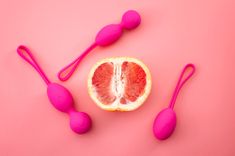 Liebeskugeln und eine halbe Grapefruit auf pinkem Hintergrund