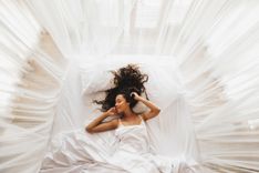Kleopatra Stellung - Abbildung einer Frau, welche in einem Bett mit weißen Vorhängen liegt
