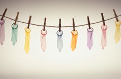 Wäscheleine, an der bunte Kondome aufgehängt sind