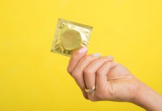 Frau hält ein verpacktes Kondom in der Hand