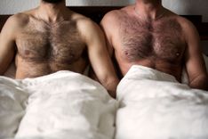 2 nackte Männer sitzen nebeneinander im Bett