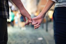 Frau und Mann laufen mit verschränkten Fingern durch die Stadt