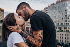Tätowierter Mann küsst leidenschaftlich eine Frau 