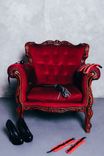 Ein roter Sessel mit High Heels und Bondage Accessoires davor