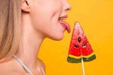Frau leckt an einem Lolli, der wie eine Melonenscheibe aussieht