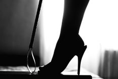 Peitsche und Frauenbein in High Heels