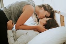 2 Frauen liegen im Bett und küssen sich innig