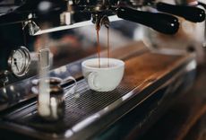 Kaffee läuft aus einer Siebträgermaschine in eine weiße Tasse,
