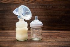 Milchpumpe und Milchflasche auf einem Holzhintergrund