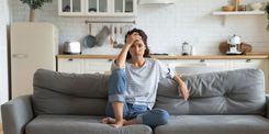 Frau sitzt auf Sofa und schaut traurig