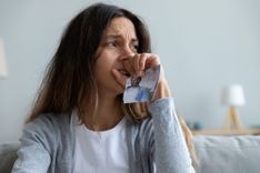 Frau schaut traurig und hält ein zerrissenes Foto in der Hand