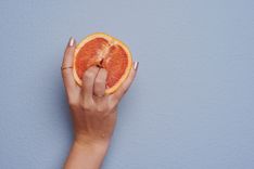 Zwei Finger, die in eine halbe Orange eingeführt werden