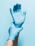 Hände mit blauen Latexhandschuhen