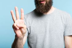 Mann hält drei Finger in die Luft