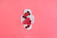 Auf einer Menstruationsbinde liegen rote Rosen
