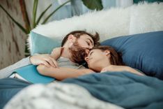Paar liegt nach dem Sex zusammen im Bett und kuschelt
