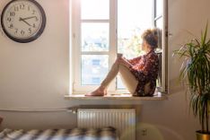 Frau sitzt nachdenklich auf dem Fensterbrett