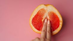 Frau führt 2 Finger in eine halbe Orange ein