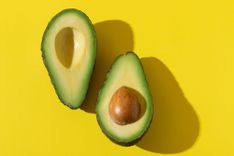 Aufgeschnittene halbierte Avocado auf gelbem Hintergrund