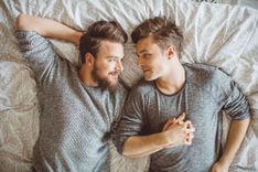 Schwules Paar liegt im Bett und sieht sich an
