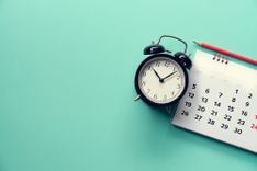 Wecker, Kalender und Bleistift auf mintfarbenem Hintergrund