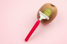 Kiwi, die rasiert wird auf rosanem Hintergrund
