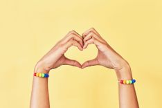 2 Hände mit Regenbogen-Armbändern formen ein Herz