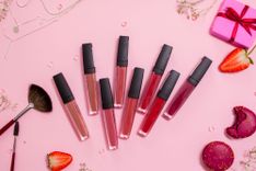 Verschiedenfarbige Lipglosse vor rosafarbigem Hintergrund 