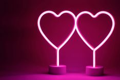 Zwei leuchtende Herzen auf rosa Hintergrund
