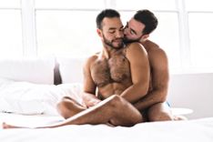 2 Männer sitzen im Bett und kuscheln