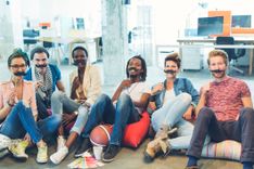 Eine Gruppe von Menschen hält sich Schnurrbärte vors Gesicht