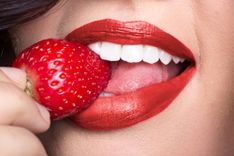 Frau mit roten Lippen beißt von Erdbeere ab