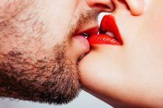 Mann und Frau mit roten Lippen küssen sich in Nahaufnahme