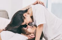Brünette Frau in weißem Shirt beugt sich über einen brünetten Mann ebenfalls im weißen T-Shirt