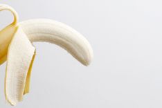 Halb geschälte Banane vor weißem Hintergrund