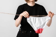 Frau hängt eine blutige Unterhose an eine Wäscheleine