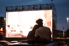 Mann und Frau kuschelnd auf einem Autodach im Autokino